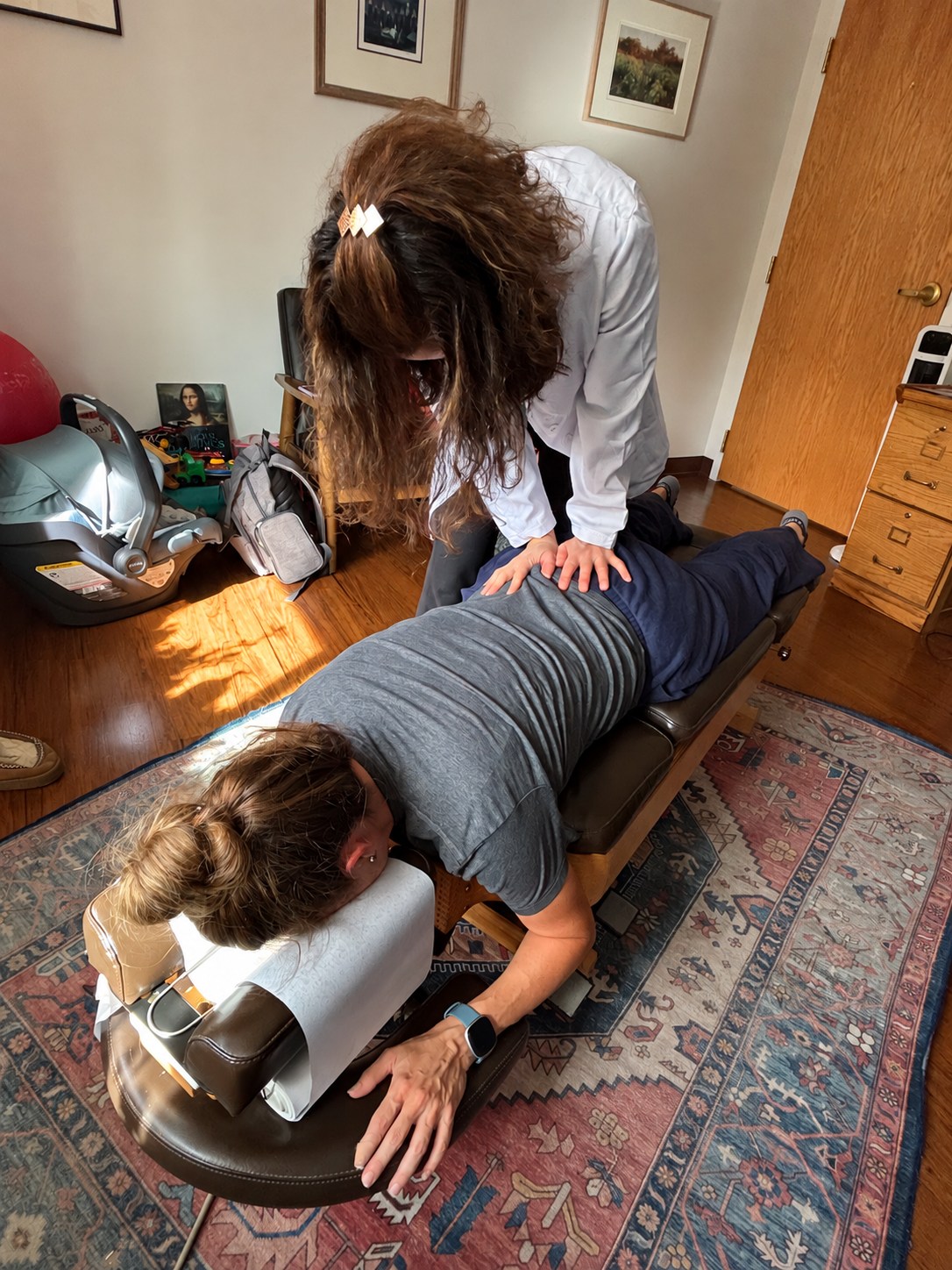 Dr. Cara Hillwig providing chiropractic care with an infant seat nearby